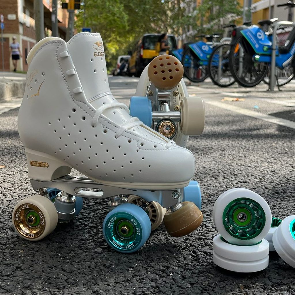 patin de gama alta de patinaje artistico, foto artistica en la calle y ruedas Roll line ice a su costado, el patin tiene una bota Edea ritmo la base es Roll line mistral y las ruedas Roll line giotto